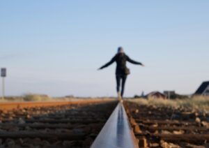 persoon lopend over evenwichtsbalk, handen wijd, op zichzelf vertrouwen